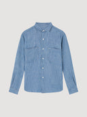 Blue chambray denim worker shirt on a light grey background. The shirt has two large chest pockets.