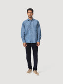 Front full body view of Coconut Residence model wearing a blue chambray denim worker shirt and navy corduroy trousers on a white background