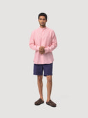 Man wearing a Red White Stripe Mandarin Collar Linen Shirt and navy shorts on a white background