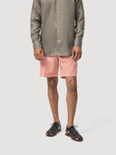 Person wearing a khaki linen shirt and red and white seersucker shorts on a white background